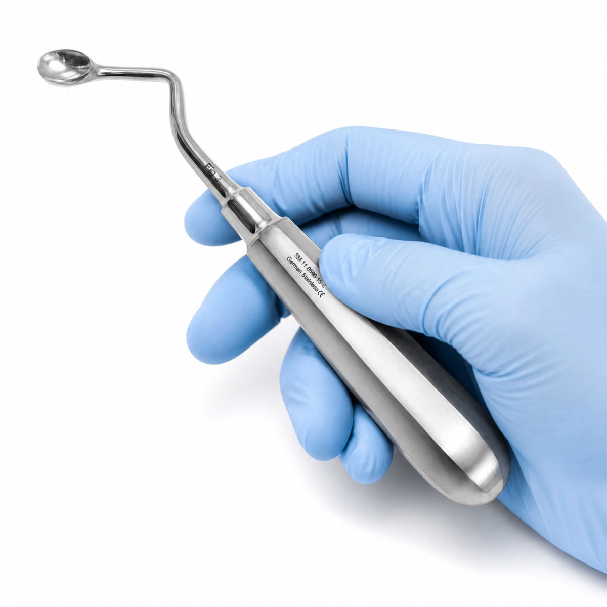 Stainless steel dental Lucas bone curette with a spoon-shaped tip and thick handle, held by a person wearing a blue nitrile glove.