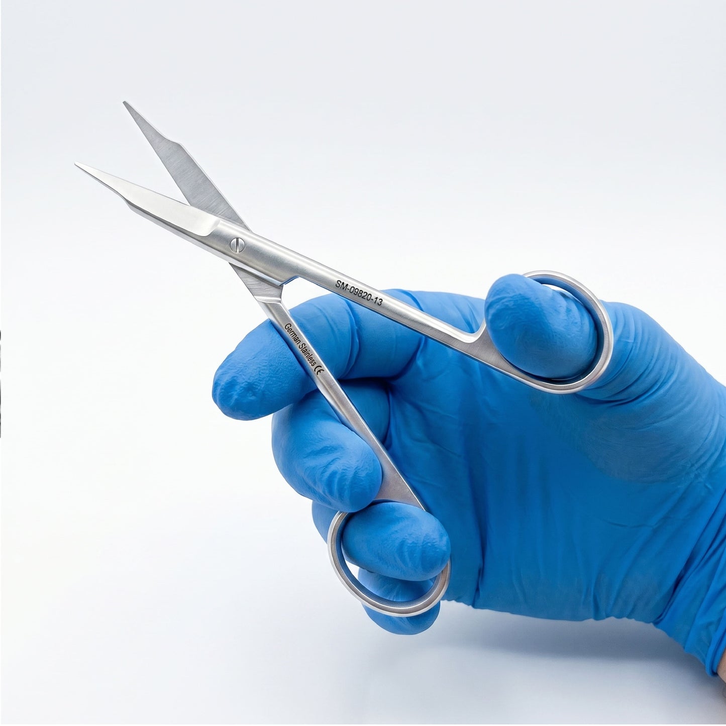 Hand wearing a blue glove holding surgical scissors on a white background