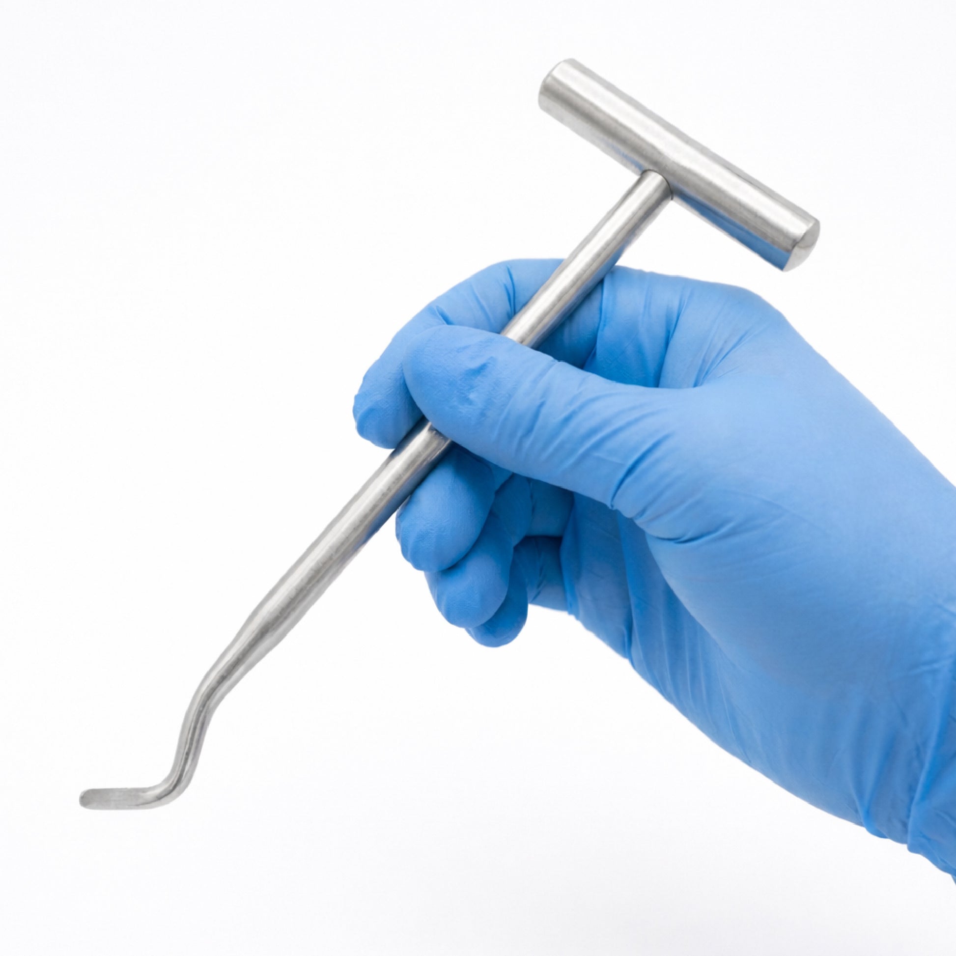 A person wearing a blue nitrile glove holding a stainless steel dental Potts elevator with a T-bar crossbar handle against a solid white background.