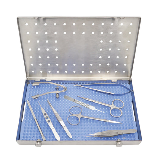 An open surgical instrument tray containing various ophthalmic instruments such as scissors, forceps, and a speculum.