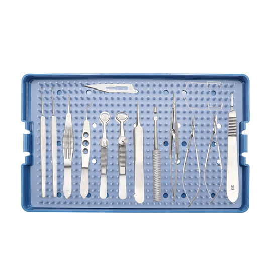 A blue sterilization tray containing a variety of stainless steel micro-surgical instruments for eye surgery, including forceps, scissors, and a speculum, arranged neatly on a silicone mat.